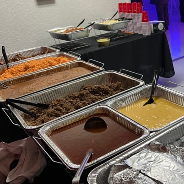 A buffet spread of Mexican food in foil trays, including rice, beans, meats, and sauces.